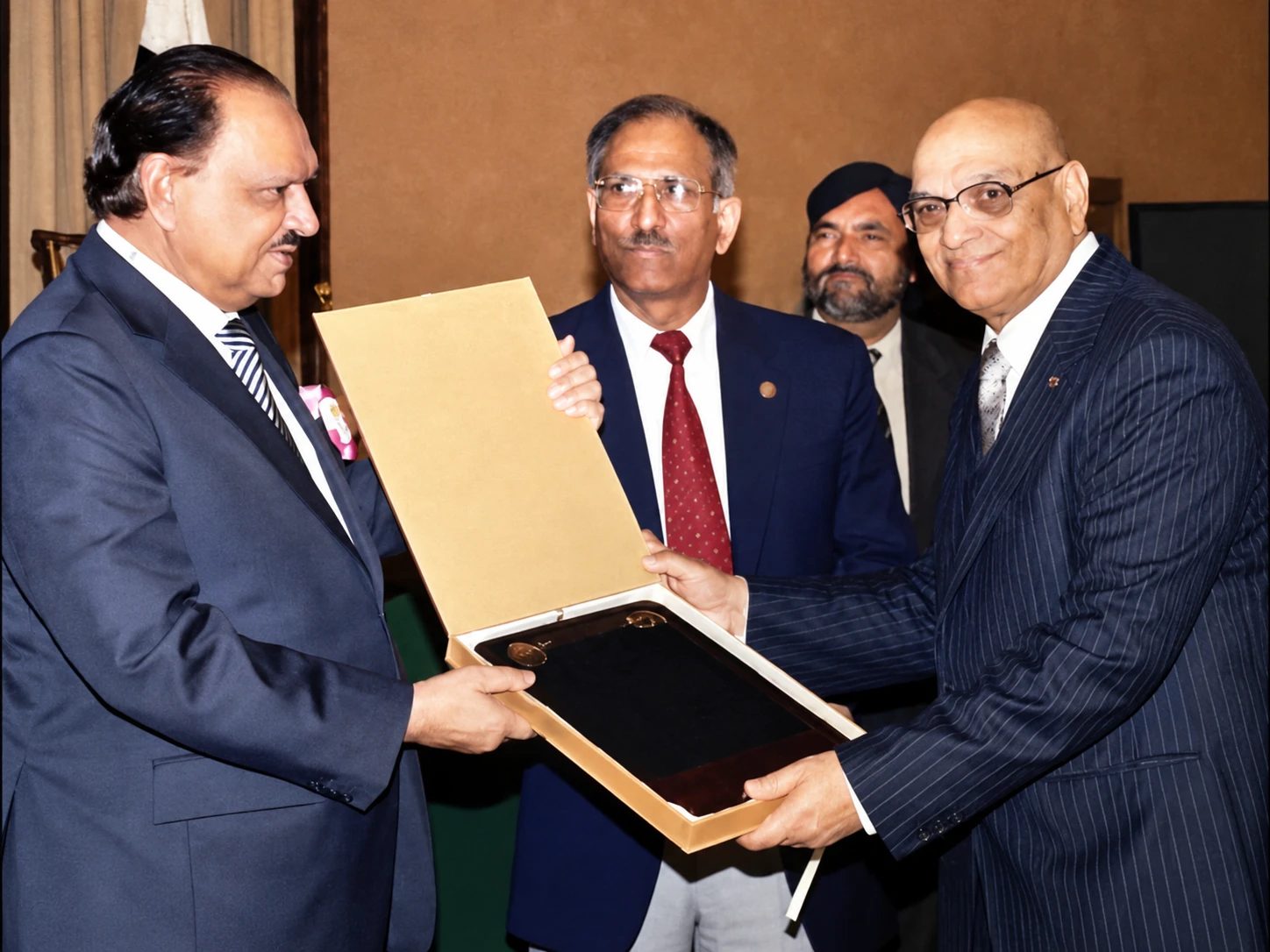 Dr. Zafar Iqbal receiving a presentation case at a formal ceremony